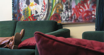 Picture of green couch with read pillows and a colorful painting behind it in the RBL