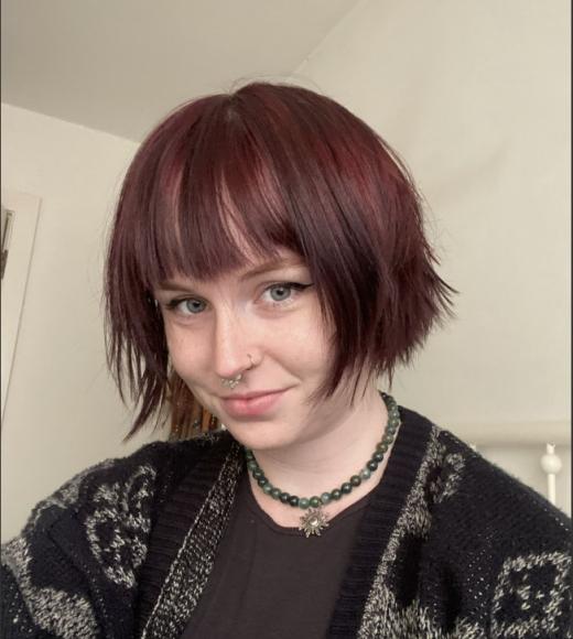 Selfie of Jenny. She is wearing a black and white sweater, with her hair in a short bob to the bottom of her ears. She has eye make up on and is wearing a necklaces.