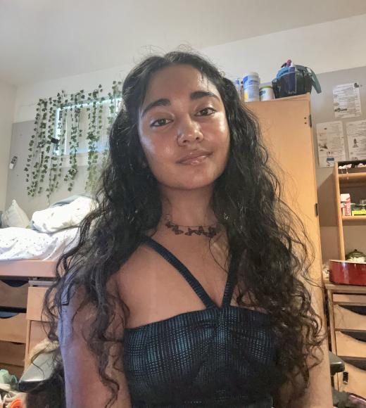 Selfie of Rishita in her room. She has long wavy hair and is wearing a black tank top.